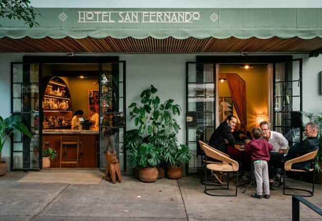 The exterior of Hotel San Fernando has mint green walls and is lined with plants.