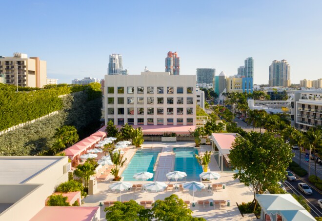 The Goodtime Hotel's pool area is flanked by pink cabanas and blue and white umbrellas.