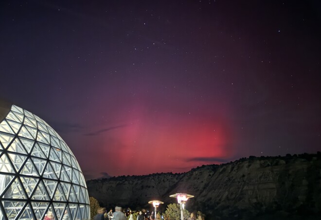 The Northern Lights glowing in hues of red at  Clear Sky Resorts Bryce Canyon with the large glass dome restaurant in the foreground