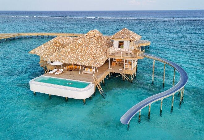 A villa at Soneva Secret in the Maldives with thatched roofs and a waterslide.