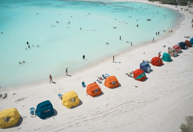 A high view of colorful sun tents in a row along Baby Beach in Aruba.