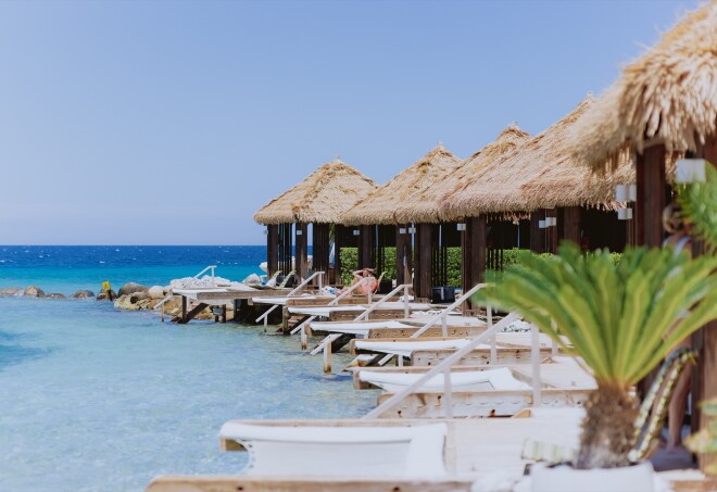 A view of palm thatched roof shade structures along the beach in Renaissance Island in the Caribbean,