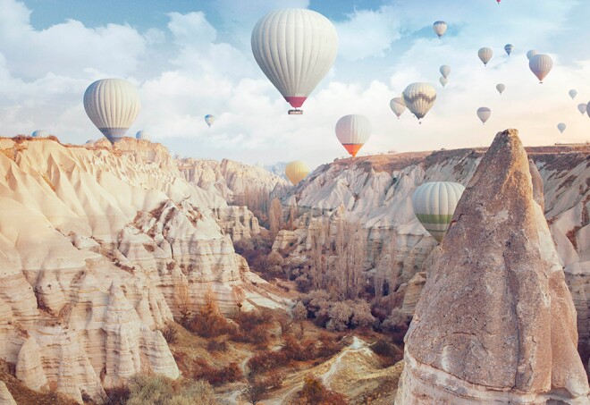 Hot air balloons floating over high desert peaks in Cappadocia